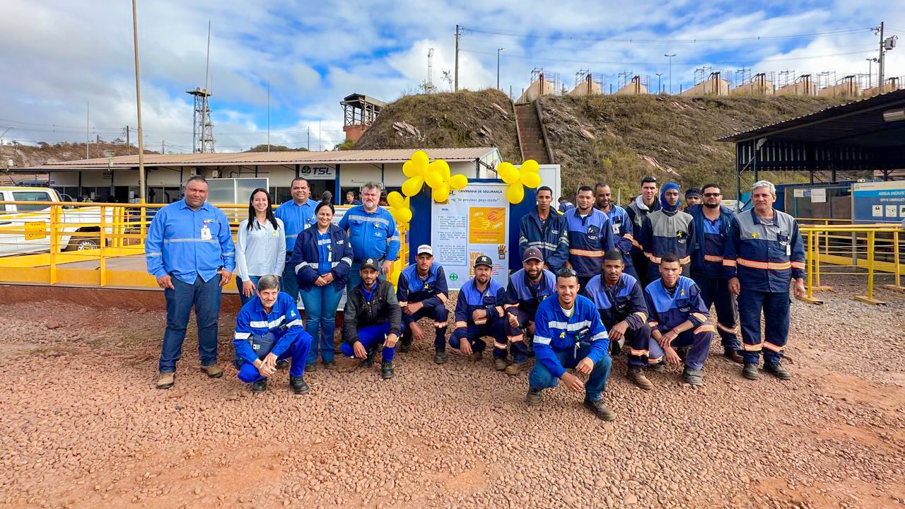 Equipe da Kesco reunida na campanha de segurança, diante do painel da campanha